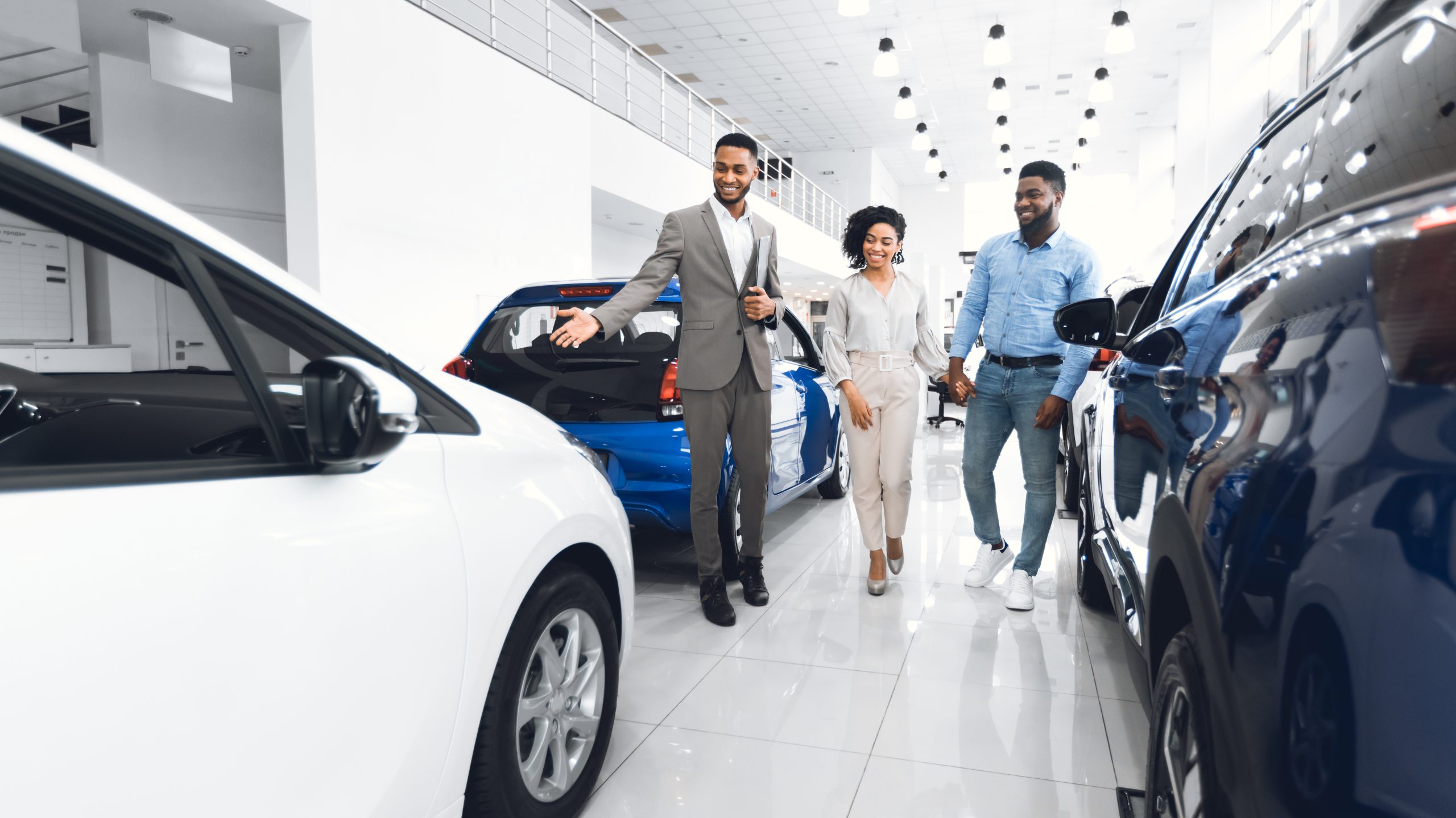 Customers viewing vehicles with a salesperson in a car showroom.